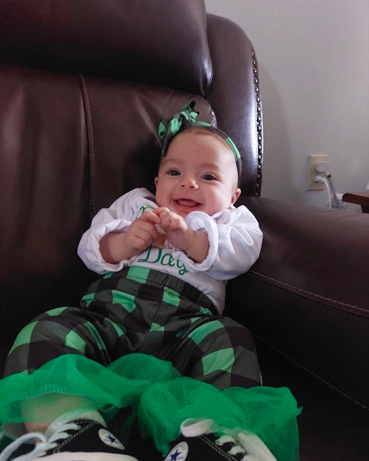 Miley joined the competition — help win amazing prizes! baby, baby_products, baby_toddler_clothing, comfort, couch, event, eye, human_body, lap, leg, living_room, pattern, person, plaid, room, sitting, sleeve, sock, tartan, throw_pillow