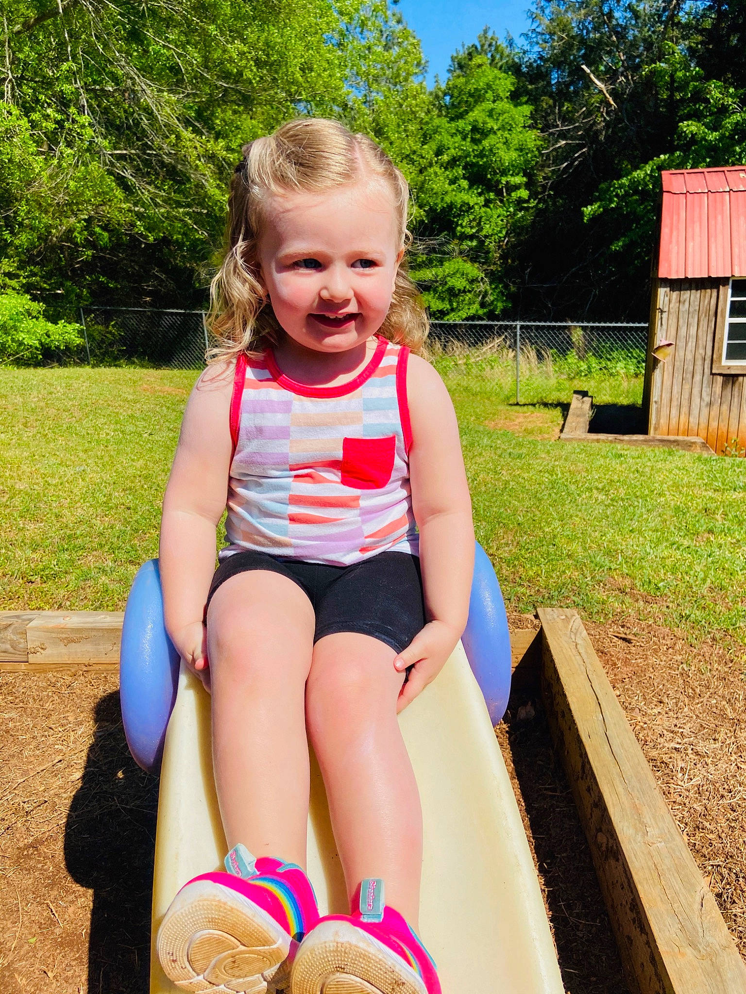 Tinsley is registered to the contest to win money with this photo: child, eye, fun, grass, happy, joy, leg, leisure, outdoor_play_equipment, people, person, pink, play, playground, public_space, recreation, sitting, skin, smile, summer