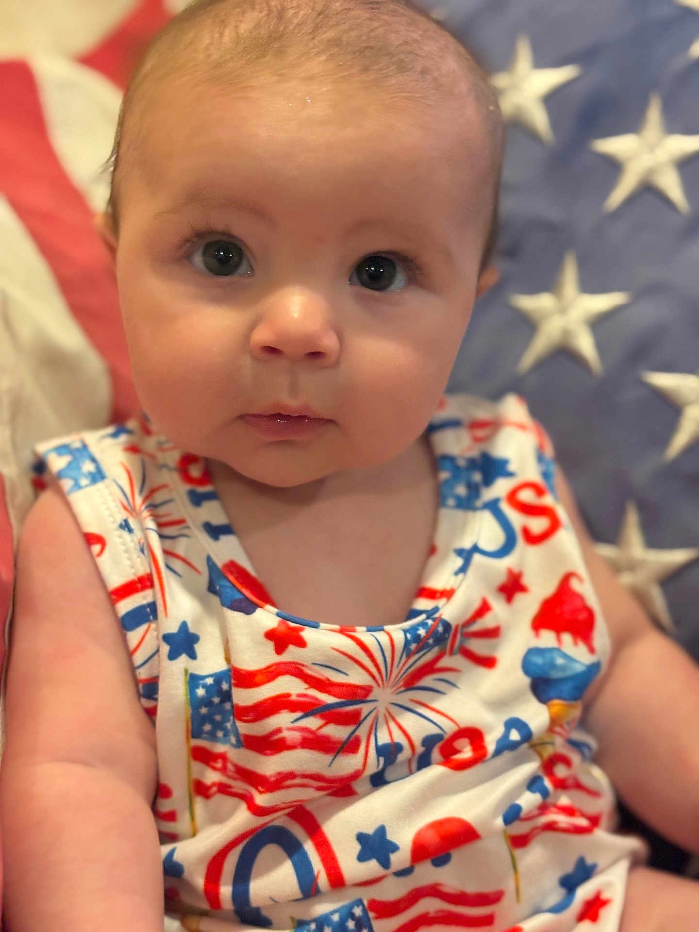 Rylie is registered to the contest to win money with this photo: baby, infant, face, eyes, clothing, pattern, stars, stripes, patriotic, red, white, blue, sitting, portrait, cute, skin, person, child, background, closeup