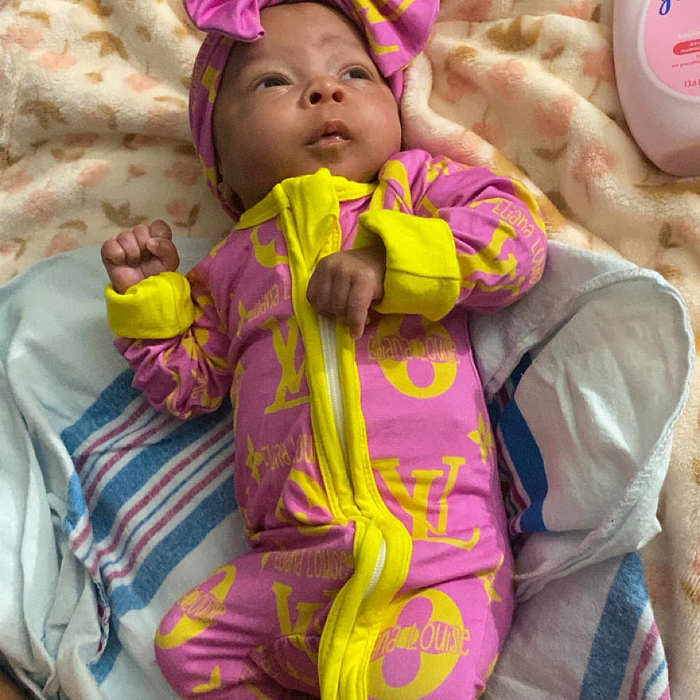 Eliana joined the competition — help win amazing prizes! baby, blanket, bottle, bow, clothing, cute, fabric, foot, hand, headwear, indoors, infant, laying_down, lotion, person, pink, portrait, soft_texture, striped, yellow