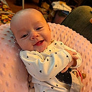 Bonnie is registered to the contest to win money with this photo: baby, child, infant, smiling, happy, portrait, close_up, indoors, blanket, pink_blanket, heart_pattern, pajamas, clothing, toy, teether, lying_down, warm_lighting, cozy, face, photography
