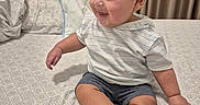 Massimo joined the competition — help win amazing prizes! toddler, child, smiling, bed, bedding, curtains, indoors, clothing, shorts, hoodie, sneakers, fabric, pattern, person, furniture, home, cute, happy, seated, portrait
