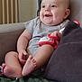 baby, blanket, child, clothing, couch, cozy, cushion, cute, expression, foot, furniture, hand, happy, head, indoor, infant, person, seated, skin, smiling
