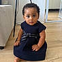 baby, black_hair, bow, child, curly_hair, cute, dress, floor, foot, furniture, home, indoor, light, looking_at_camera, person, portrait, sitting, small_hands, wall, wooden_floor