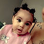 arm, baby, bunny_print, child, closeup, clothing, curious, cute, face, indoor, infant, person, pigtails, pink_bib, portrait, seated, skin, tattoos, tongue_out, young_child