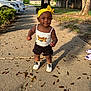 toddler, child, outdoor, sidewalk, yellow_headband, white_shoes, black_shorts, sunlight, shadow, tree, leaves, smile, cute, person, summer, casual_clothing, park, happy, walking, daytime