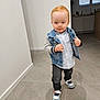 toddler, child, indoor, floor, denim_jacket, shirt, pants, sneakers, walking, red_hair, person, shoes, shadow, modern_interior, tile_floor, window, curtain, cabinet, casual_clothing, cute