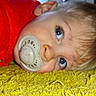 baby, blue_eyes, carpet, child, closeup, cute, expression, face, hair, indoors, infant, lying_down, pacifier, portrait, red_clothing, resting, skin, soft_texture, yellow_carpet, young_child