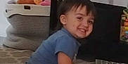 Leo is registered to the contest to win money with this photo: child, toddler, smiling, indoor, carpet, toy, basket, furniture, table, shirt, shorts, person, hair, floor, home, cute, happy, playful, barefoot, living_room