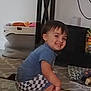 child, toddler, smiling, indoor, carpet, toy, basket, furniture, table, shirt, shorts, person, hair, floor, home, cute, happy, playful, barefoot, living_room