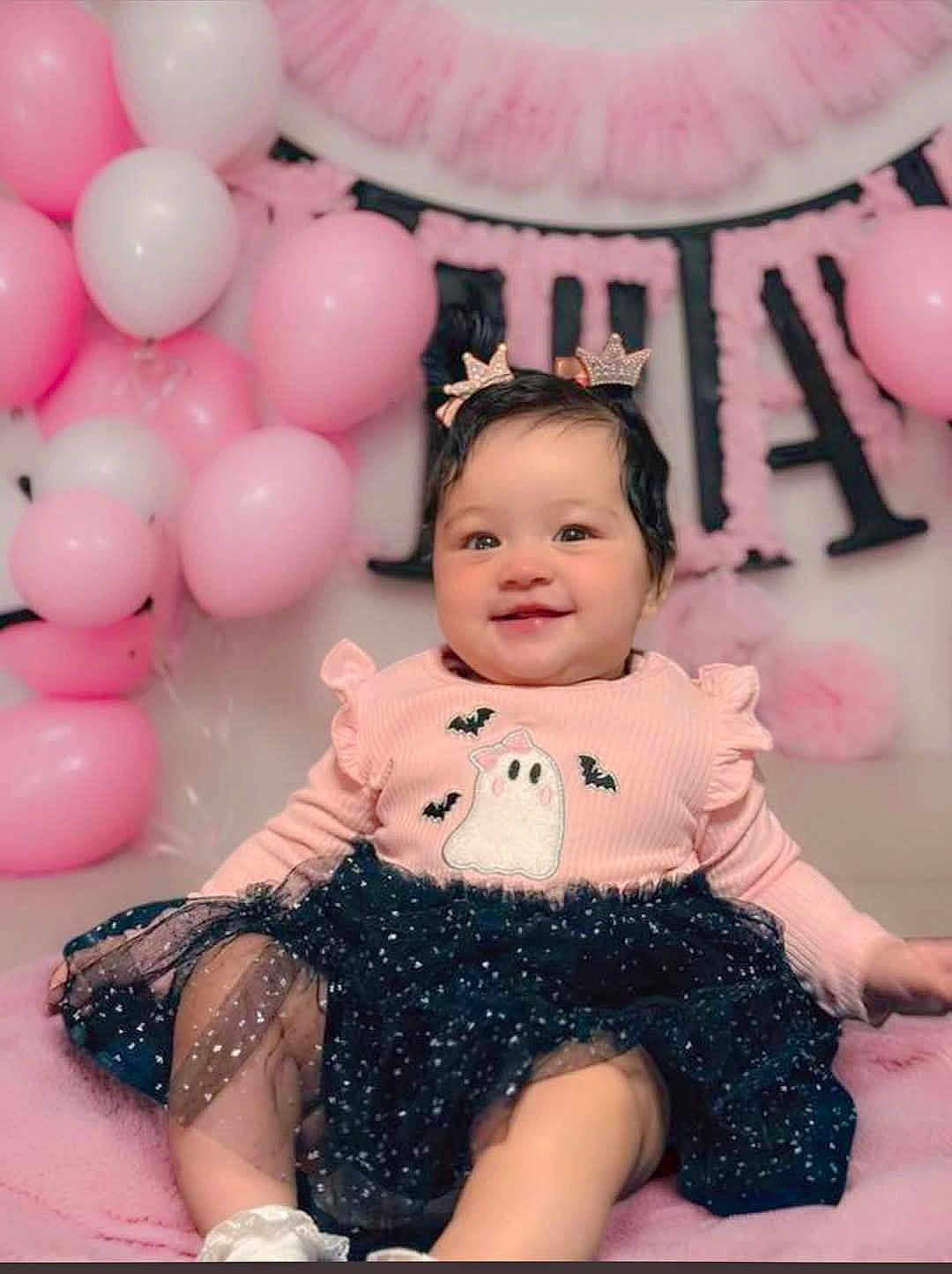 Nairobi is registered to the contest to win money with this photo: baby, child, girl, smiling, pink, balloons, dress, ghost, bats, hair_clips, crown, cute, happy, celebration, party, tutu, sitting, soft, indoors, portrait