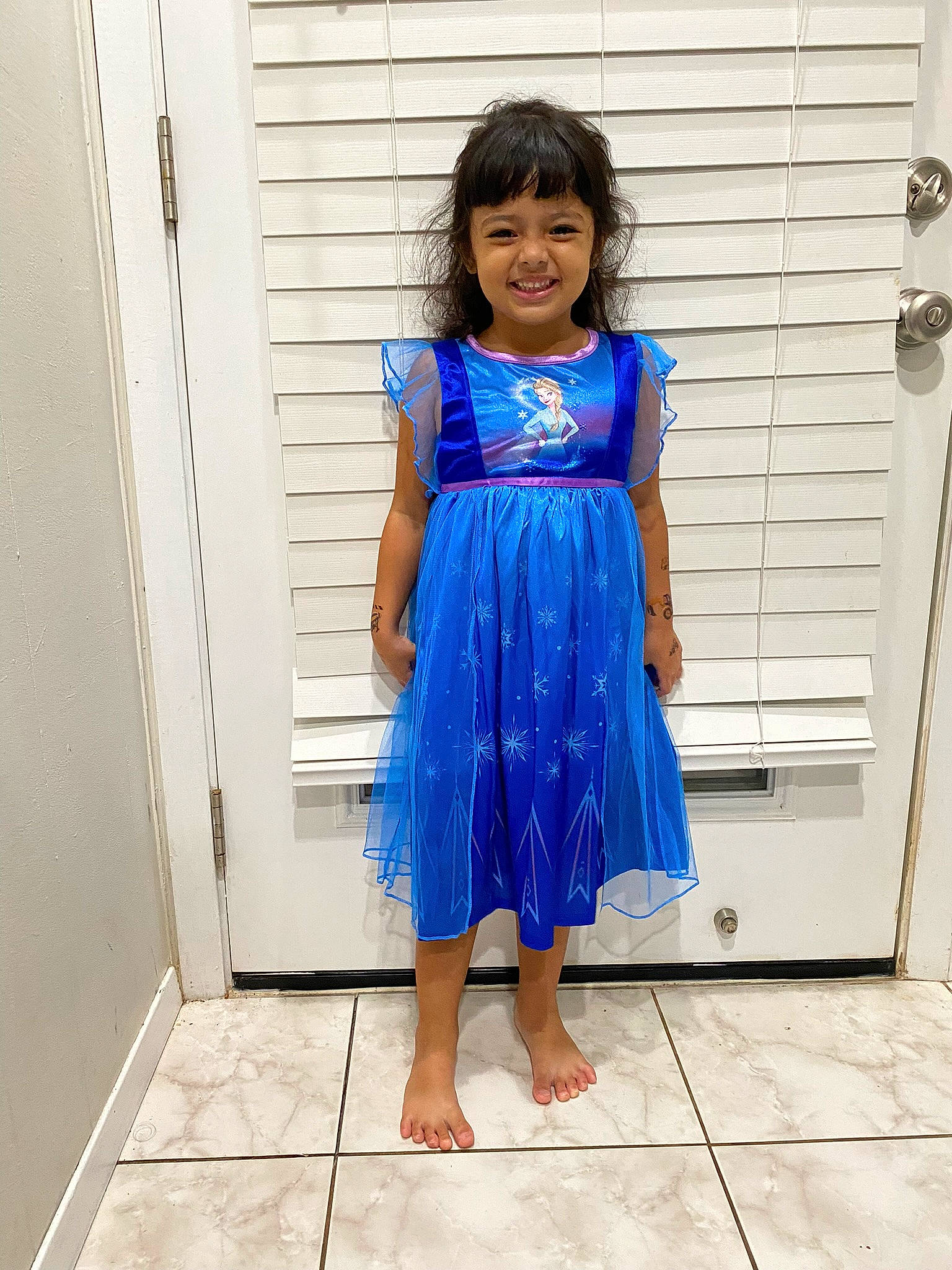 Naiya is registered to the contest to win money with this photo: child, day_dress, door, electric_blue, fashion_design, flooring, formal_wear, happy, human_leg, joy, long_hair, neck, one_piece_garment, outerwear, pattern, person, shoulder, sleeve, smile, toddler