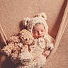 baby, sleeping, teddy_bear, costume, fluffy, cute, infant, soft_texture, hammock, beige, cozy, child, portrait, resting, plush_toy, warm, adorable, newborn, snuggling, peaceful