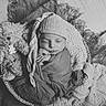 newborn, baby, sleeping, swaddled, hat, basket, blanket, teddy_bear, soft_texture, black_and_white, portrait, cozy, infant, peaceful, cute, resting, headwear, wrapped, child, indoors