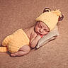 newborn, baby, sleeping, knitted_hat, knitted_pants, lion_costume, yellow, cute, infant, soft_pillow, beige_background, resting, peaceful, portrait, child, cozy, costume, animal_theme, small, adorable