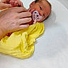 Anaya Cienna is registered to the contest to win money with this photo: newborn, baby, pacifier, yellow_blanket, hospital_bed, adult_hands, medical_setting, infant, lying_down, person, skin, head, face, blanket, bed, care, human, pacifier_clip, newborn_care, tender_moment