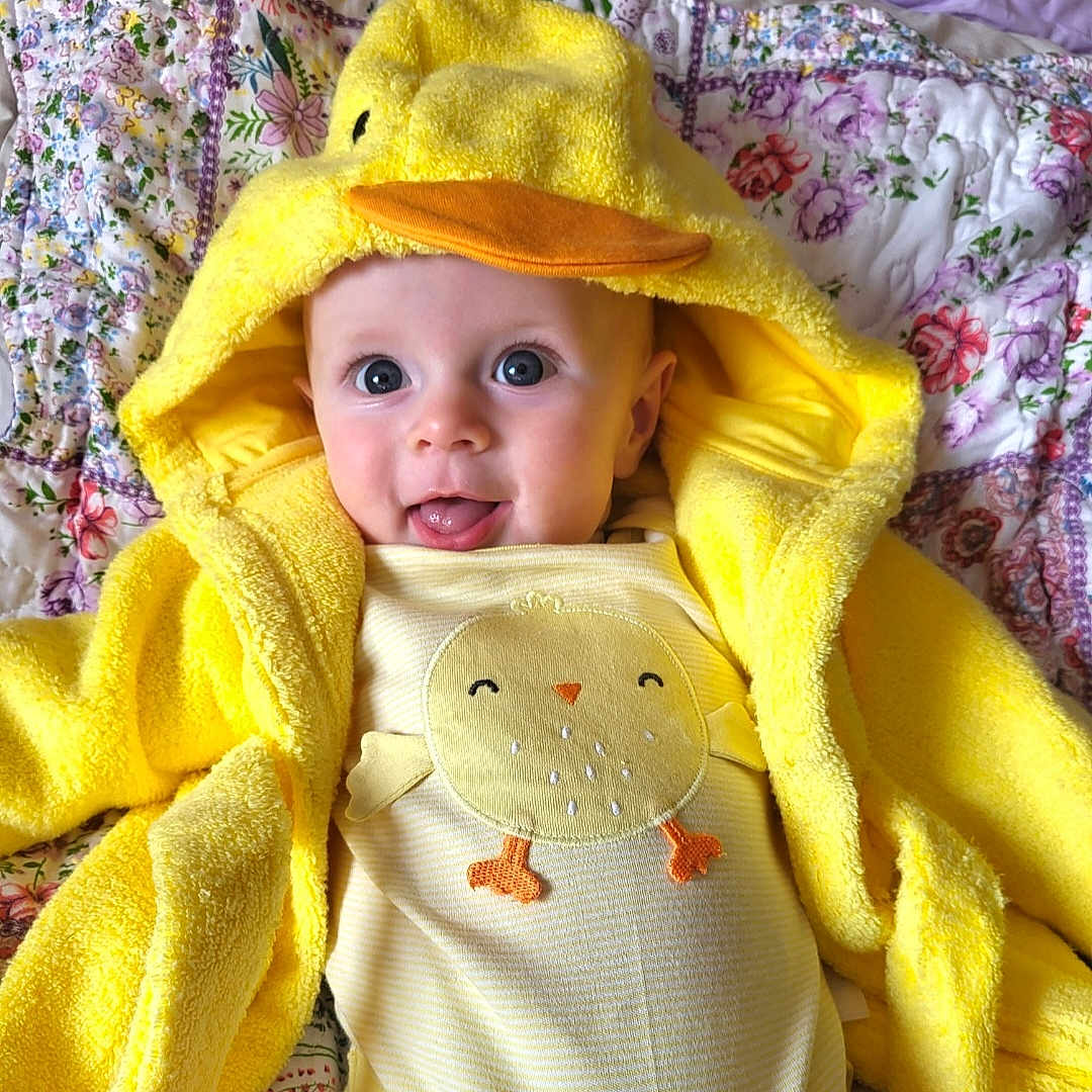 James is registered to the contest to win money with this photo: baby, bed, blanket, bonnet, clothing, coat, cushion, face, furniture, happy, hat, head, homedecor, newborn, person, photography, portrait, quilt, smile, towel