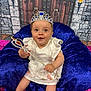 baby, child, tiara, scepter, white_dress, crown, blue_cushion, purple_cushion, castle_backdrop, stone_wall, wooden_door, torch, flame, happy, smiling, sitting, indoor, portrait, costume, playful
