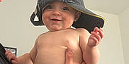 Olivia is registered to the contest to win money with this photo: baby, child, smiling, hat, cap, diaper, shirtless, indoor, person, adult_hand, holding, face, eyes, cheeks, skin, human, young, cute, happy, portrait