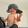 baby, child, smiling, hat, cap, diaper, shirtless, indoor, person, adult_hand, holding, face, eyes, cheeks, skin, human, young, cute, happy, portrait