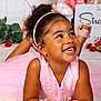 Kataléya a rejoint le concours — aidez-le/la à gagner de superbes lots ! background, child, closeup, curly_hair, cute, decor, flower, girl, hands, happy, headband, indoor, joyful, lying_down, pink_dress, portrait, pretty, smiling, white_rug, young