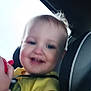 Benjamin is registered to the contest to win money with this photo: toddler, child, car_seat, yellow_shirt, smiling, indoor, toy, baby, seatbelt, car_window, person, face, happy, blurry, hair, skin, clothing, transportation, seat, infant