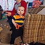 toddler, man, video_game_controller, couch, toy, carpet, window, curtains, box, clothing, glasses, indoor, person, child, living_room, furniture, sock, basket, jeans, plush_toy