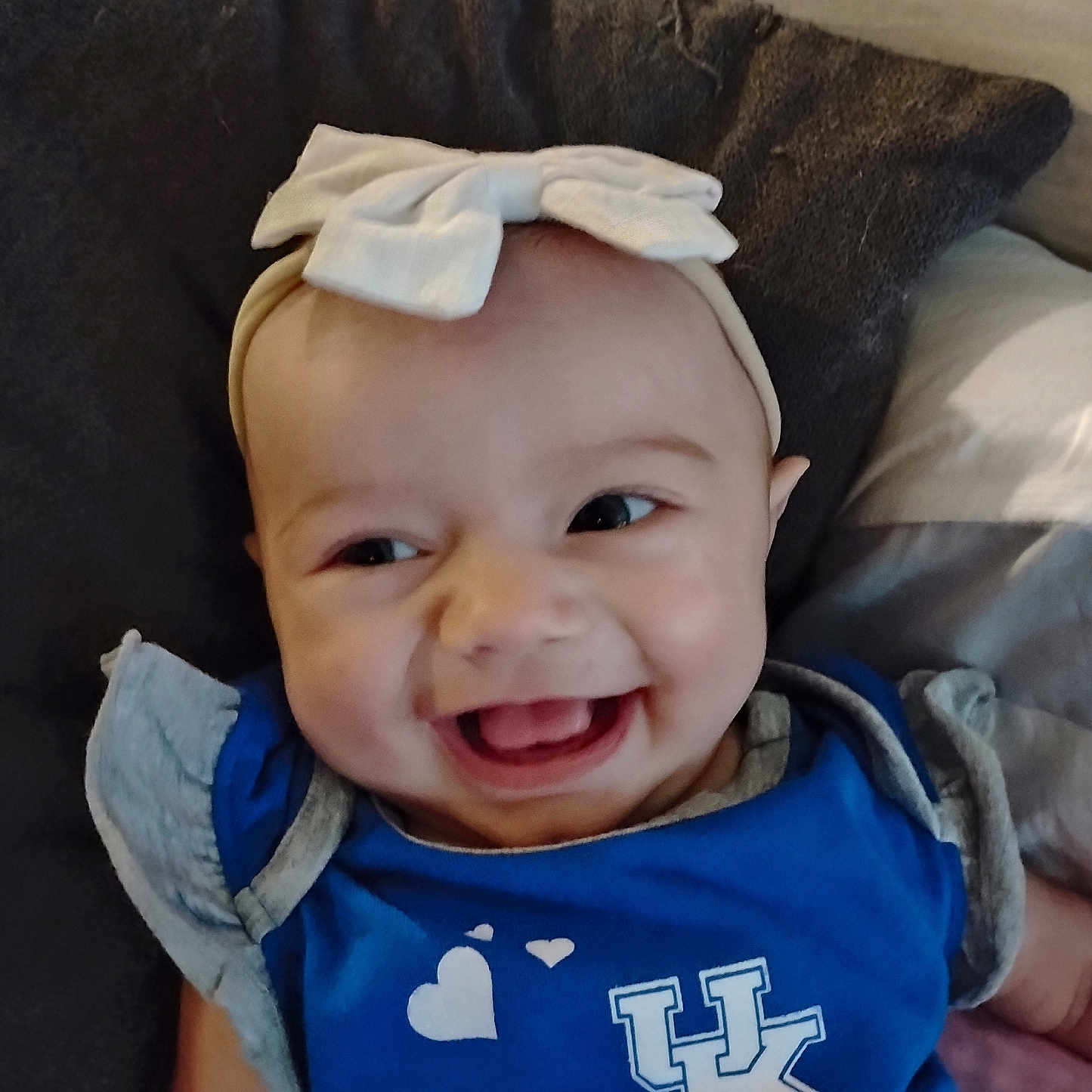 Sammi is registered to the contest to win money with this photo: baby, baby_girl, blue_shirt, cheerful, child, closeup, clothing, cute, face, happy, headband, headwear, indoor, infant, kentucky, person, pillow, portrait, smiling, young_child