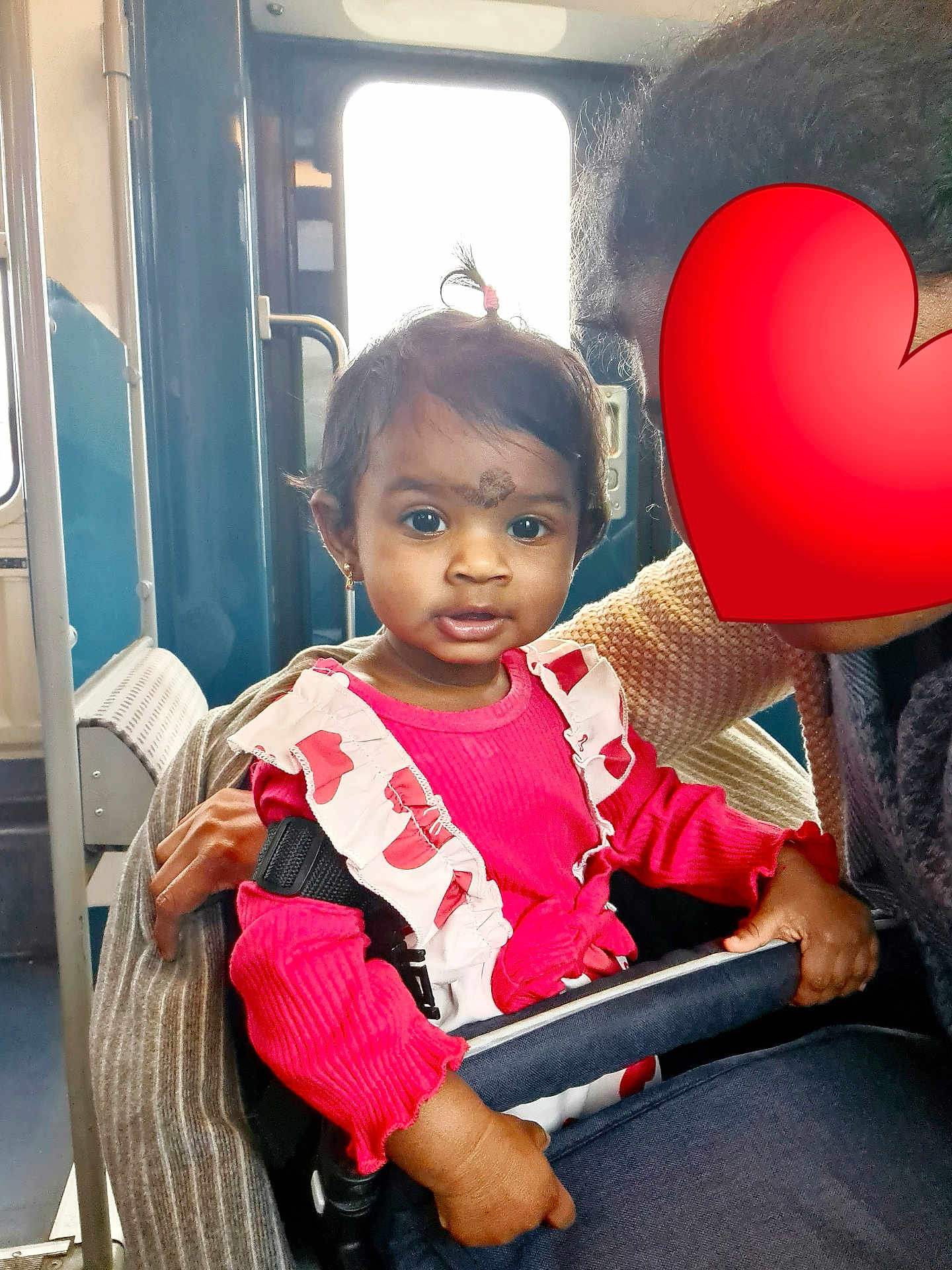 Sonakshi a rejoint le concours — aidez-le/la à gagner de superbes lots ! child, toddler, pink_clothing, pony_tail, stroller, safety_bar, adult, heart_emoji, bus_interior, window, hand, seat, curious, indoor, person, transportation, public_transport, face, holding, casual