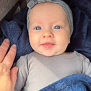 Louise participe au concours pour gagner de l'argent avec cette photo : baby, infant, blanket, headband, hand, smiling, blue, striped, bow, clothing, face, skin, eyes, person, cute, cozy, soft, happy, portrait, closeup