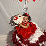 baby, child, red_dress, headband, plush_toy, basket, tinsel, heart_decorations, valentines_day, rose_petals, smiling, cute, indoor, celebration, holiday, festive, adorable, happy, portrait, decor