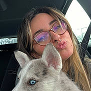 Alpine participe au concours pour gagner de l'argent avec cette photo : woman, person, glasses, septum_piercing, puppy, dog, husky, blue_eyes, car_interior, seatbelt, selfie, close_up, fur, ears, nose, pet_owner, affectionate, window, puckered_lips, seat