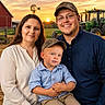 Parker joined the competition — help win amazing prizes! child, family, parents, toddler, portrait, smiling, outdoor, farm, sunset, golden_hour, tractor, barn, windmill, rural, countryside, camouflage_cap, blue_shirt, button_up_shirt, family_photo, agriculture