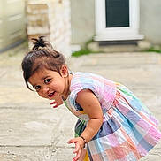 Risha joined the competition — help win amazing prizes! toddler, child, dress, colorful, outdoor, curious, barefoot, bracelet, anklet, smiling, candid, portrait, playful, young_child, person, hair_tied, pavement, door, background_blur, sunlight