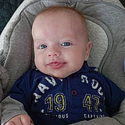 Tiago a rejoint le concours — aidez-le/la à gagner de superbes lots ! baby, infant, smiling, blue_eyes, clothing, shirt, sitting, cozy, blanket, face, child, cute, portrait, hand, indoor, young, person, head, happy, seat