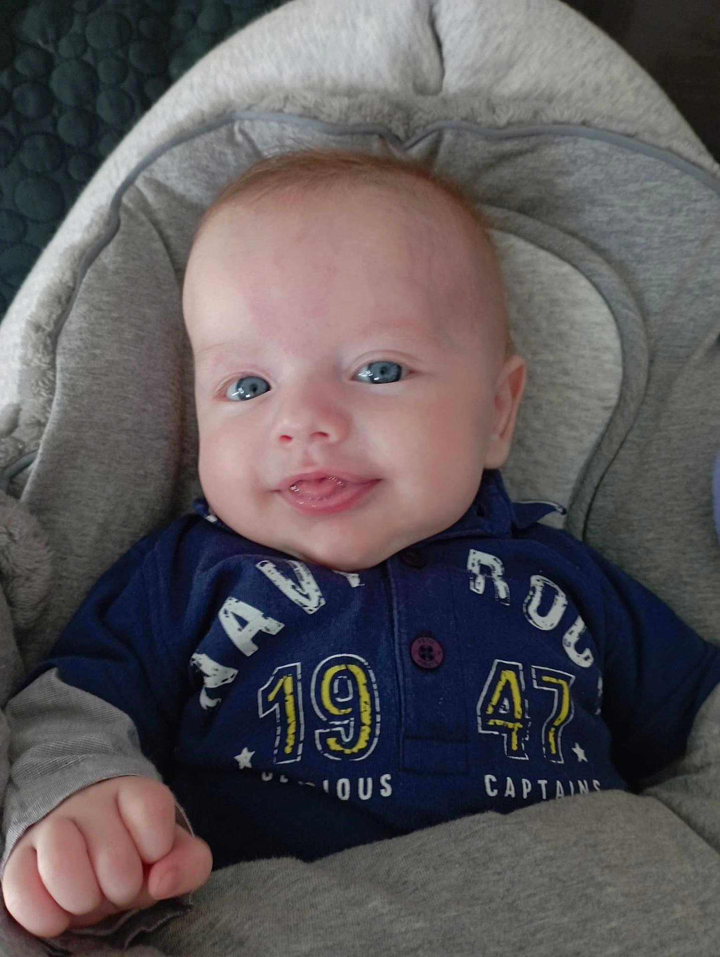 Tiago a rejoint le concours — aidez-le/la à gagner de superbes lots ! baby, infant, smiling, blue_eyes, clothing, shirt, sitting, cozy, blanket, face, child, cute, portrait, hand, indoor, young, person, head, happy, seat