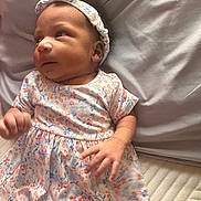 Sophia joined the competition — help win amazing prizes! baby, infant, floral_dress, headband, bed, pillow, blanket, hand, face, skin, person, child, newborn, cute, soft_texture, lying_down, indoors, sleepwear, young, portrait
