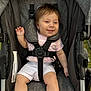 baby, child, stroller, smile, happy, pink_shirt, white_shorts, sitting, seatbelt, outdoor, grass, cute, infant, person, young_child, portrait, one_person, clothing, hand, foot