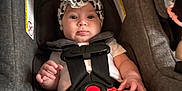 Lainey is registered to the contest to win money with this photo: accessory, baby, car_seat, child, clothing, cute, headband, indoor, infant, looking, person, pout, safety_harness, seat, secure, shorts, sitting, straps, white_shirt, young_child