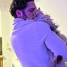 person, cat, indoor, sweater, fluffy_cat, hug, affection, purple_light, cozy, pet, fur, shoulder, facial_expression, home, relaxed, cute, animal, warmth, portrait, love