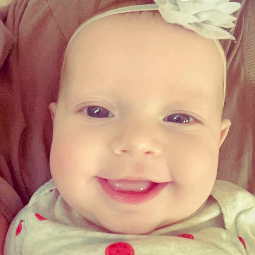 Mckenna is registered to the contest to win money with this photo: accessories, baby, bodypart, cushion, face, flower, happy, head, headband, homedecor, laughing, mouth, newborn, person, photography, plant, portrait, rose, smile, teeth