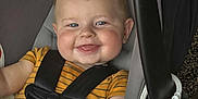 Nico is registered to the contest to win money with this photo: baby, child, car_seat, blue_eyes, blanket, striped_shirt, smile, happy, infant, cute, safety_harness, indoors, face, cheeks, person, blue_blanket, toddler, young_child, cozy, seat