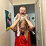 Nico is registered to the contest to win money with this photo: baby, child, person, smiling, happy, indoor, hallway, painting, mickey_mouse, red_shirt, blonde_hair, holding, fun, joy, shoulders, home, door, wall, carpet, clothing