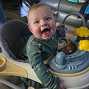 Nico joined the competition — help win amazing prizes! baby, baby_walker, smiling, toy, indoor, person, man, couch, furniture, clothing, happy, child, play, floor, home, relaxing, colorful, seat, joy, infant