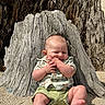 baby, child, sitting, tree_stump, sand, outdoor, sunlight, clothing, cute, happy, hands, smile, nature, skin, barefoot, infant, shorts, patterned_shirt, daylight, relaxing