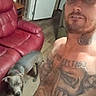 animal, cap, casual, curious, dog, door, furniture, home, indoor, leather_chair, living_room, man, open_door, person, pet, portrait, red_chair, selfie, tattoos, wood_floor