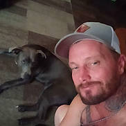 Jasper joined the competition — help win amazing prizes! man, dog, cap, chain, tattoo, rug, floor, indoor, casual, selfie, pet, animal, human, beard, relaxed, furniture, room, wooden_floor, carpet, portrait