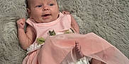 Astrid is registered to the contest to win money with this photo: baby, barefoot, child, clothing, cute, diaper, face, fluffy_rug, happy, head, indoors, infant, lying_down, newborn, pink_dress, playful, skin, small, smiling, soft_texture