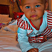 Theresa Amarii is registered to the contest to win money with this photo: baby, child, bed, red_bow, striped_clothing, crawling, indoor, lamp, pillow, blanket, headband, cute, infant, person, face, hand, foot, expression, room, furniture