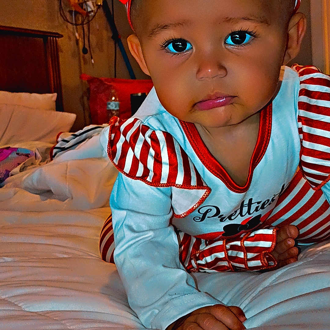 Theresa Amarii is registered to the contest to win money with this photo: baby, bed, blanket, child, crawling, cute, expression, face, foot, furniture, hand, headband, indoor, infant, lamp, person, pillow, red_bow, room, striped_clothing